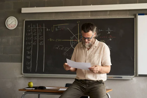 Male teacher prepares or corrects exams in the classroom. — Stock Photo, Image
