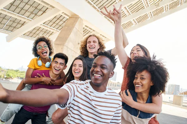 Ομάδα φίλων διασκεδάζουν στην πόλη. Νεαροί διαφυλετικοί μαθητές βγάζουν σέλφι. Έννοια της φιλίας, της τεχνολογίας, των διακοπών. — Φωτογραφία Αρχείου