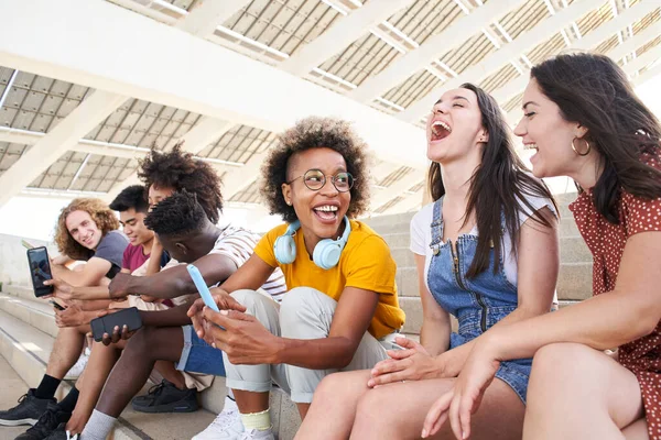 Groupe multiethnique de jeunes amis utilisant des téléphones cellulaires et s'amusant. — Photo