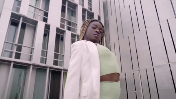 Mujer bailando en la calle. Una joven negra se mueve rítmicamente. Tiene el pelo largo y trenzas. Bonita bailarina. Las chicas expresiones faciales cambian de forma. — Vídeos de Stock