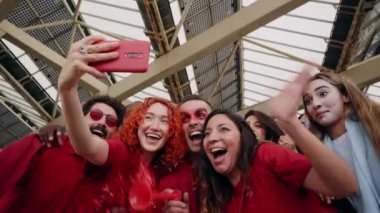 Neşeli erkek ve kadın taraftarlar stadyumda maç izlerken telefonlarıyla video kaydediyorlar..