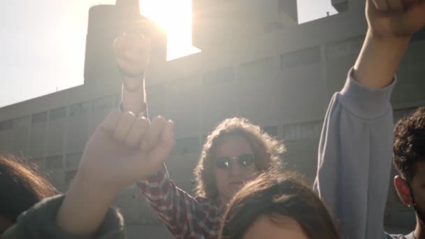 En grupp aktivister som står och tittar på kameran med näve i luften under en protestmarsch. Ungdomar som protesterar för att skydda de medborgerliga rättigheterna. Långsamma rörelser. — Stockvideo