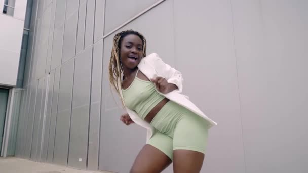 Танцующая улыбающаяся женщина счастливая африканская танцовщица наслаждается фанки хип-хоп движениями исполняя фристайл танец в городе. — стоковое видео
