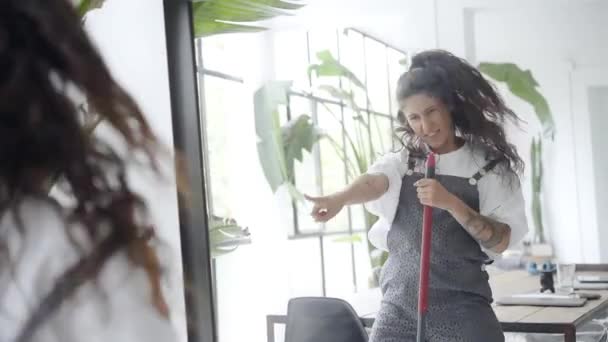 Nette Hausfrau tanzt mit Besen. Hausreinigung und Unterhaltung während der Quarantäne. Frau hat Spaß zu Hause bei der Hausarbeit. — Stockvideo