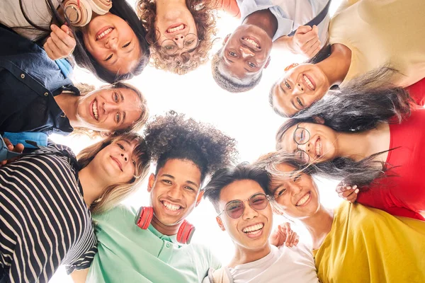 Bajo ángulo de un grupo de estudiantes están juntos, felices y sonrientes. Rostros de jóvenes adolescentes mirando a la cámara, abrazándose. — Foto de Stock