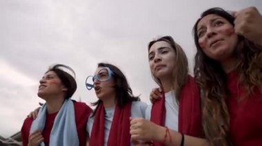 Bir grup bayan taraftar takımlarının spor müsabakalarındaki zaferini coşkuyla kutluyor. Stadyumun tribünlerinde eğlenen kadınlar..