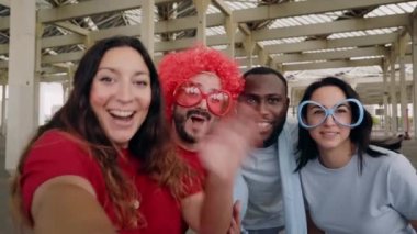 POV özçekimi. Bir grup taraftar stadyumdan spor takımı için tezahürat yaparken bir video görüşmesi yapıyor. Çok ırklı bir grup insan stadyumdaki maçı izlerken selfie çekiyor..
