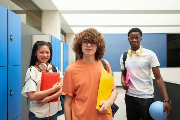 Πορτρέτο τριών φυλετικά διαφορετικών μαθητών που κοιτούν την κάμερα στο σχολείο. Γκέι αγόρι στο σχολείο με τους συμμαθητές του. — Φωτογραφία Αρχείου