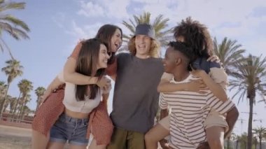 Farklı ırklardan gelen bir grup genç dışarıda gülüp eğleniyor. Tatil kavramı, eğlence, boş zaman, yaz.
