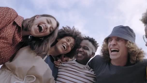 Bajo ángulo de un grupo de jóvenes sonrientes multiétnicos mirando a la cámara. En el fondo un hermoso cielo con nubes. — Vídeo de stock