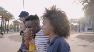 Gençler yürüyor ve gülüyor. Mutlu dostluklar, bir grup melez insan dışarıda neşeli bir arada..