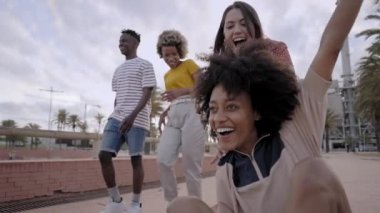 Longboard 'da oturan Afrikalı kız ve bayan arkadaşları onu öne itip caddeyi koşarak geçiyorlar. Genç arkadaşlar birlikte eğleniyor. Maceracı genç ruhlar aktif spor hayatı.