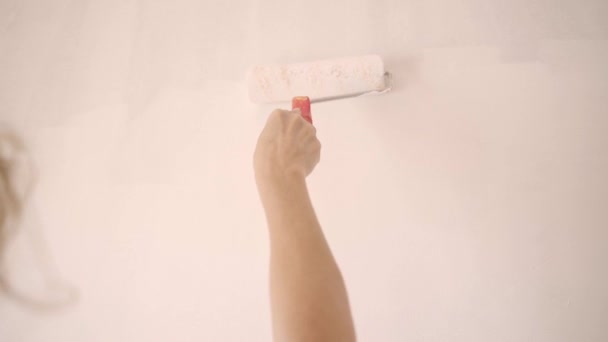 Mujer feliz moviendo rodillo de pintura en la pared en un nuevo hogar. Sonriente pintura familiar dentro de una casa nueva. Joyful pintora femenina que trabaja en un nuevo apartamento durante la reparación del hogar. — Vídeo de stock