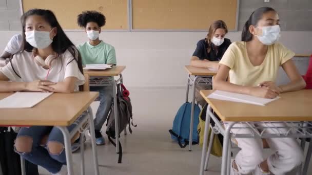 De vuelta a la pandemia escolar. Los jóvenes estudiantes con máscaras protectoras aprenden en clase de las lecciones de los profesores. — Vídeo de stock