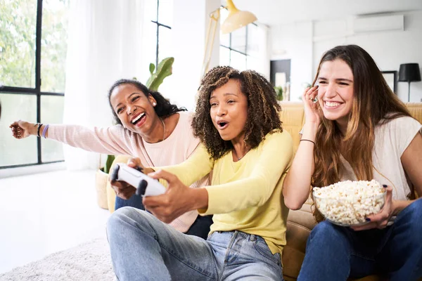 若い友人のグループは自宅でビデオゲームを一緒にプレイします。ポップコーンを祝うと食べる唯一の女性ゲーマー. — ストック写真