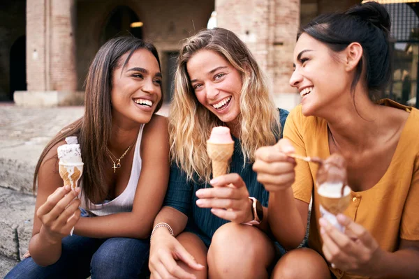 Ragazze adolescenti ridendo e mangiando coni gelato seduti all'aperto godendo la loro vacanza estiva. — Foto Stock