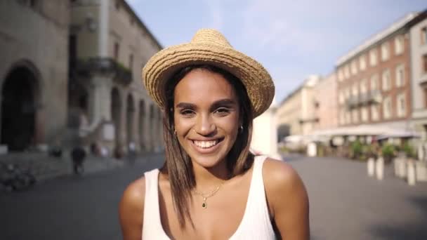 Mujer africana muy hermosa riendo con hermosa sonrisa. Joven turista con sombrero en una ciudad romana.Concepto de vacaciones y personas positivas. — Vídeos de Stock