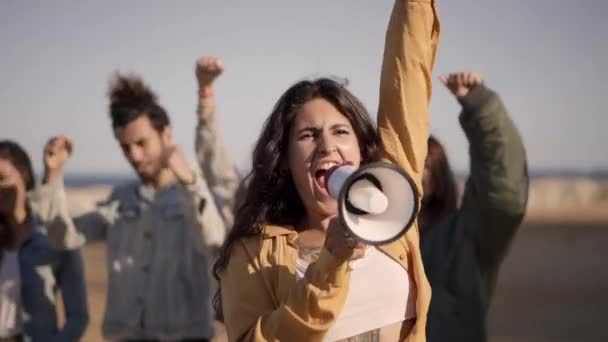 Bij protest schreeuwt de vrouw met megafoon die haar vuist in menigte opheft. Mensen die demonstreren voor hun rechten. — Stockvideo