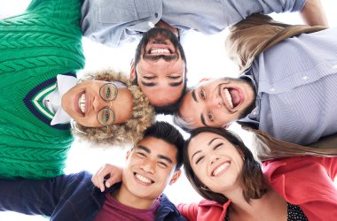 Çok ırklı arkadaş grubu eğleniyor. Bir grup insan kameraya bakıp gülerek daireler çiziyor. Arkadaşlık kavramı.
