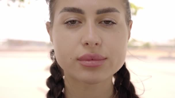 Közelkép egy gyönyörű kaukázusi nőről, aki komoly kamerába néz. Női szépség a szabadban. — Stock videók