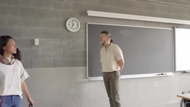 Volver a clase con los jóvenes estudiantes entrando en el aula. El profesor espera a que los estudiantes se sienten. — Vídeos de Stock