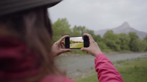 自然の中で風景の彼女の携帯電話で写真を撮る女性のバックビュー. — ストック動画