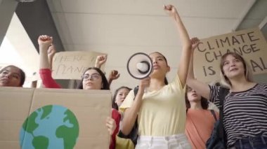 Multi-ethnic group of teenagers at a protest march, carrying signs with environmental and conservation slogans. Ecological awareness protest by students.