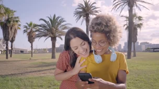 年轻。女混血儿一边看着手机，一边指着屏幕上有趣有趣的东西。技术、连接、应用、在线、社交媒体的概念. — 图库视频影像