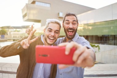 Mutlu eşcinsel çift akıllı telefonuyla gülümseyen selfie çekiyor. Homoseksüel insanlar birlikte eğleniyor..