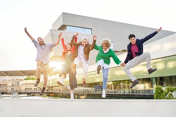 Diversitate grup fericit de prieteni sărind împreună în campus. — Fotografie, imagine de stoc