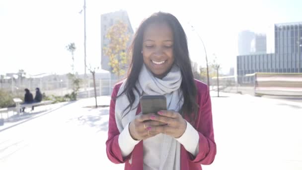 Exitosa joven mujer de negocios hermosa usando el teléfono mientras camina al aire libre en el centro financiero en una ciudad — Vídeos de Stock