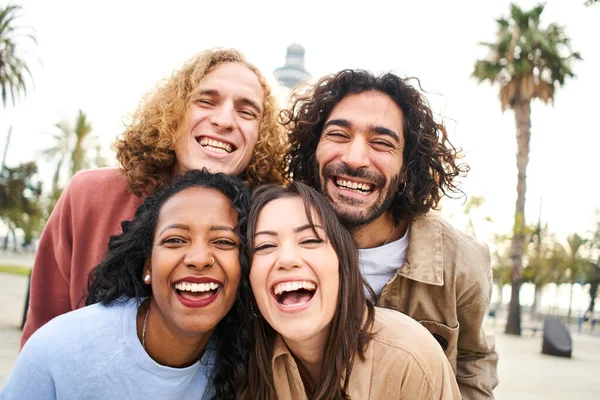 Ομάδα τεσσάρων πολυεθνικών νεαρών φίλων που διασκεδάζουν. Χαμογελώντας χαρούμενους ανθρώπους κοιτάζοντας την κάμερα σε εξωτερικούς χώρους. — Φωτογραφία Αρχείου