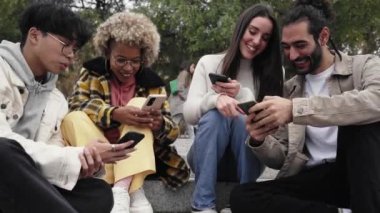 Dört arkadaş cep telefonundan komik bir şey izliyoruz. Mutlu insanlar telefon kullanır ve eğlenirler.