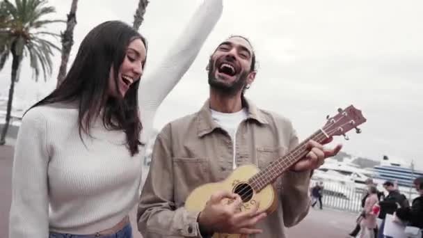 Roligt glad och kärleksfull par dans utomhus på gatan sång och spela gitarr. Man och kvinna ha kul under sin semester i staden — Stockvideo