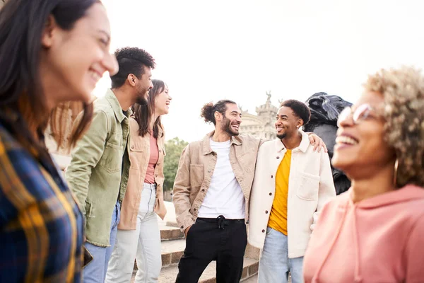 Youth culture. Group of young people laughing and talking outdoors in the city. Happy friends having fun together