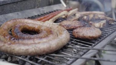 Lezzetli ve sulu sosisler ateşte ızgara yapıyor. Izgarada et pişir. Közde pişen ızgara burgerlerin üzerinde. Aileyle yaz tatili.