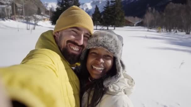 Usmívající se selfie veselého páru venku v zasněžených horách. Mladí šťastní zamilovaní lidé. Milovníci přírody mobilní telefon video. — Stock video