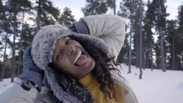 Mulher quente em roupas de neve desfruta de um dia na floresta nevada. Menina se divertindo jogando feliz olhando para a câmera. — Vídeo de Stock