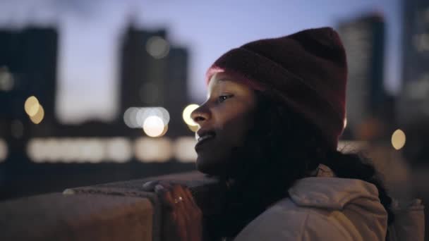 Close-up van een aantrekkelijke vrouw die 's nachts naar het uitzicht op de stad kijkt. — Stockvideo
