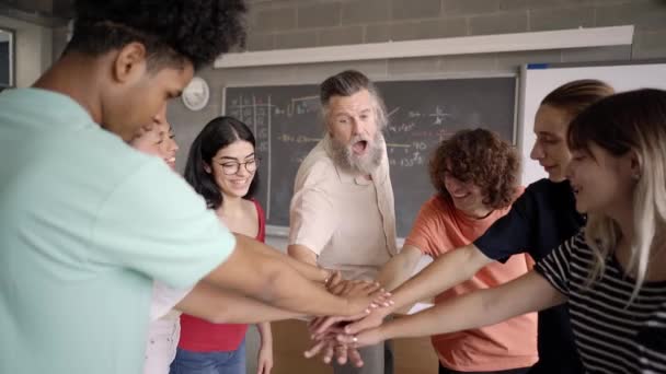 Een groep gelukkige studenten staken hand in hand met de leraar. De professor kijkt naar de camera. — Stockvideo