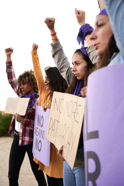 Pionowe zdjęcie grupy kobiet maszerujących na drogę w proteście. Młoda kobieta ze znakiem protestu przeciwko wzmocnieniu pozycji kobiet. — Zdjęcie stockowe