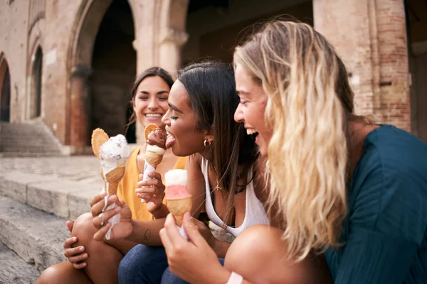Tre giovani donne che mangiano coni gelato nella turistica città romana europea in una calda giornata estiva durante le loro vacanze — Foto Stock