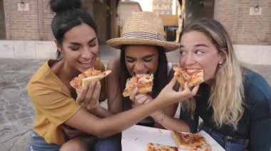 Şehirde pizza yiyen mutlu kız arkadaşlar. Üç kadın turist grubu eğleniyor. Bir kız diğerini besler. Yaşam tarzı ve arkadaşlık kavramı