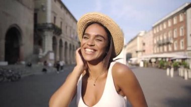 Güzel kız kameraya gülümserken çok mutlu görünüyor. Modern şehir merkezinde güzel saçlı melez çekici genç bir kadın. Portreler.