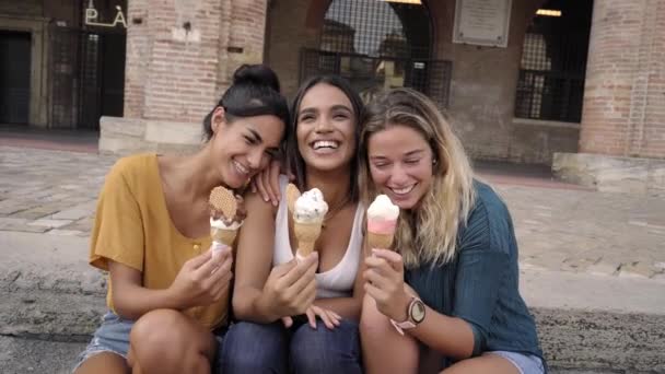 Gelukkig levendige jonge vrouwelijke studenten eten ijs kegels lachen en grappen in de hete zomerzon — Stockvideo