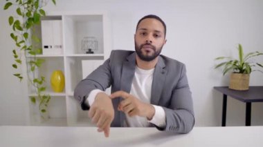 Kamerada Afro-Amerikalı bir iş adamının kameraya bakıp geç kaldığını gösteren bir video görüntüsü var. Toplantıya başlamadan ve kameraya konuşmadan önce selamlama.