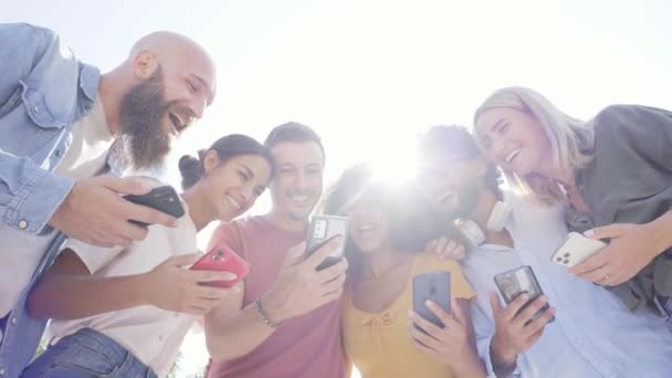 Bajo ángulo de Multiracial feliz grupo de amigos utilizando el teléfono y sonriendo juntos fuera. Personas adictas a la tecnología y las redes sociales — Vídeo de stock