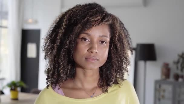 Portrait of a beautiful young adult woman serious expression face. African girl in casual looking at camera with. Confident mixed race relaxing at home. — Stock Video