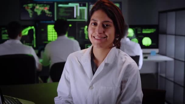 女性医療笑顔の医師は、カメラを見て。幸せな女性科学者を生物応用科学研究所で研究する。ホワイトコートのエンジニアが実験を行う背景. — ストック動画