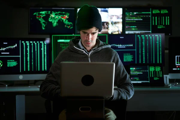 Front Shot from to Hacker Breaking into Corporate Data Servers from His Underground Hideout. Place has dark atmosphere, multiple displays — Foto de Stock